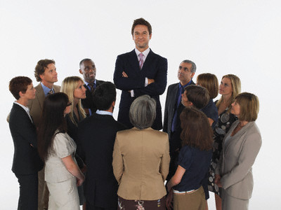 Group of Businesspeople Staring at Tall Man --- Image by © moodboard/Corbis